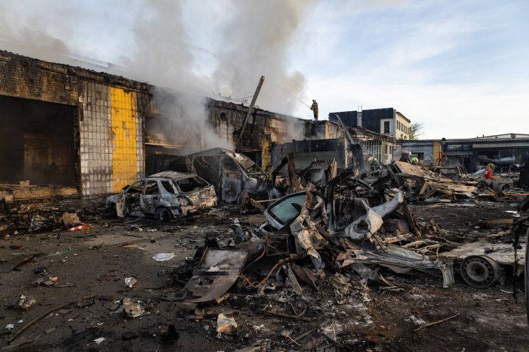 Smoke rises from a building near wrecked cars as firefighters battle a blaze following Russian missile strikes amid Russia's invasion of Ukraine, in Kyiv early on September 8, 2026.