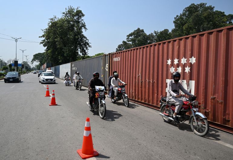 afp_6ab3be05d71e-1790164485 Commuters ride past shipping containers placed around Islamabad’s Red Zone on September 18, 2026 ahead of opposition party Pakistan Tehreek-e-Insaf (PTI) protest demanding the release of former Prime Minister Imran Khan. (Photo by Farooq NAEEM / AFP)