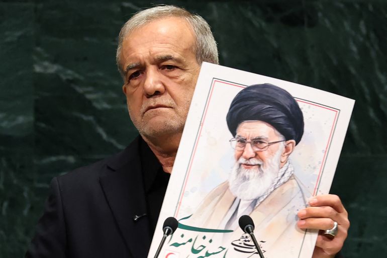 afp_6ab74f4f4288-1790398287 TOPSHOT - Iran's President Masoud Pezeshkian speaks as he holds a picture of Ali Khamenei, former Supreme Leader of Iran, during the 81st United Nations General Assembly at the United Nations Headquarters in New York, on September 23, 2026. (Photo by TIMOTHY A. CLARY / AFP)