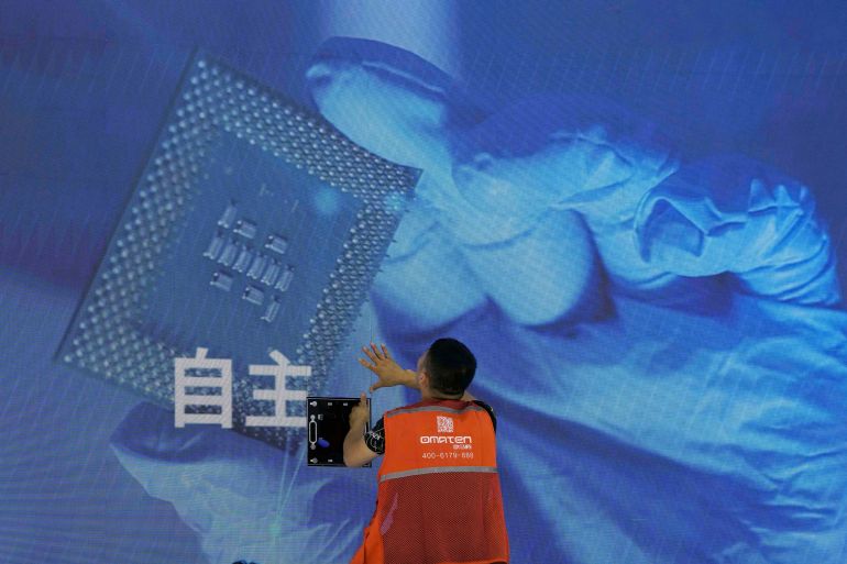 A worker checks the display panel showing a computer chip and the Chinese words for "Independence" at the booth for Chinese supercomputer manufacturer Sugon during the World AI Conference in Shanghai, Wednesday, July 5, 2023. China's government appealed to Japan on Monday, July 24, not to disrupt the semiconductor industry after curbs on exports of Japanese chip-making technology took effect, adding to technology restrictions Washington and its allies have imposed on China on security grounds. (AP Photo/Ng Han Guan)