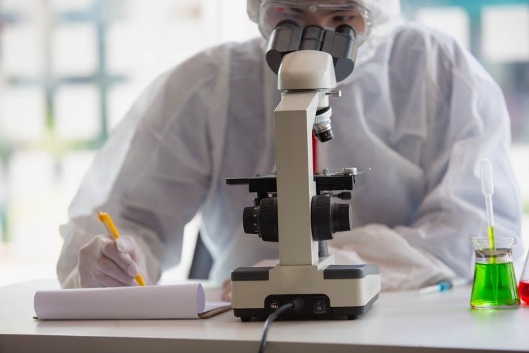 The doctor is testing a sample of biological tubes contaminated by Corona-virus Covid 19 and searching for a vaccine or Syrup against the virus. In the laboratory and film samples of infected lung; Shutterstock ID 1902025987; purchase_order: aljazeera ; job: ; client: ; other: