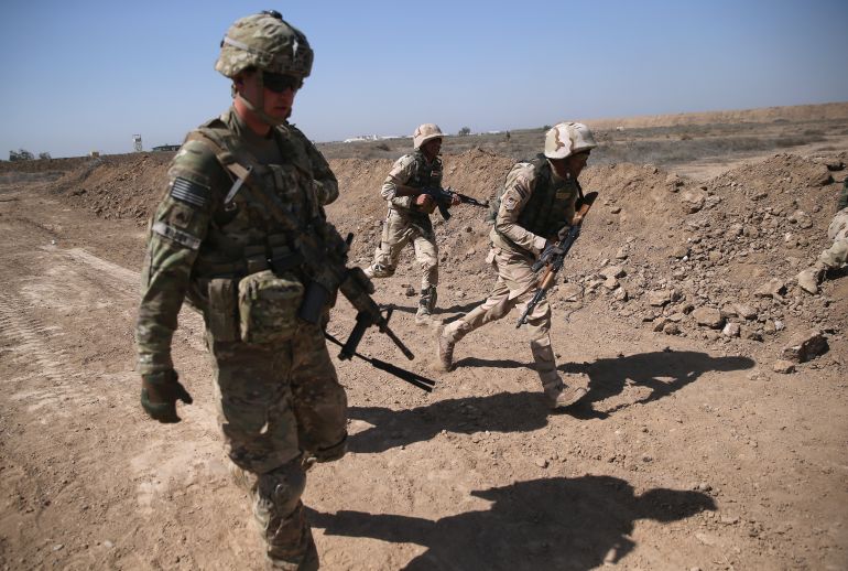 TAJI, IRAQ - APRIL 12: A U.S. Army trainer (L), instructs Iraqi Army recruits at a military base on April 12, 2015 in Taji, Iraq. U.S. forces, currently operating in 5 large bases throught Iraq, are training thousands of Iraqi Army combat troops, trying to rebuild a force they had origninally trained before the U.S. withdrawal from Iraq in 2010. Members of the U.S. Army's 5-73 CAV, 3BCT, 82nd Airborne Division are teaching members of the newly-formed 15th Division of the Iraqi Army, as the Iraqi government launches offensives to try to recover territory lost to ISIS last year. (Photo by John Moore/Getty Images)