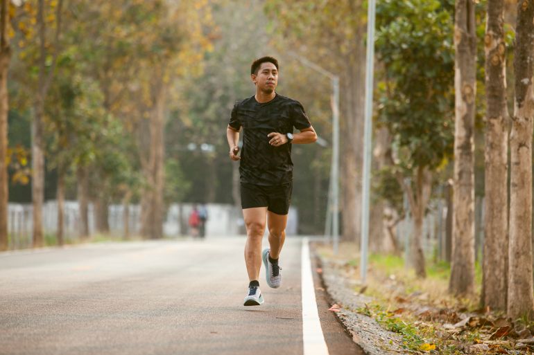 gettyimages-1303177729-1790094521 Asian sportman jogging and checking smart watch between workout jogging outdoor - stock photo