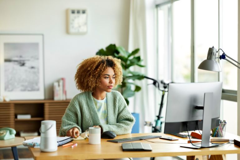 gettyimages-1355125382-1788886154 Businesswoman using computer at desk. Female professional is working at home office. She is looking at desktop PC.