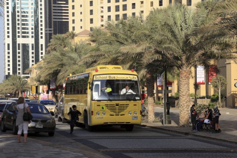 Yellow School Bus in Dubai - stock photo Dubai, United Arab Emirates - January 11, 2012: Pupil brought back home by the Yellow School Bus in Dubai Jumeirah Beach Residence, UAE. Bus driver stopped the bus and is watching the boy getting off the bus and crossing the street safe.