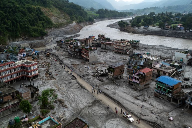 A drone view of people walking on a road and houses in mud, following deadly flash floods and mudslides at Devighat, Nuwakot district, Nepal, August 29, 2026. REUTERS/Athit Perawongmetha