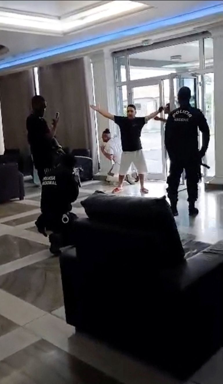 reuters_6aae7588-1789818248-1 A police officer points a firearm at a migrant deported by the United States to Equatorial Guinea at Hotel Bamy in Malabo, Equatorial Guinea, September 5, 2026, in this screengrab from video. Video obtained by REUTERS/Handout via REUTERS THIS IMAGE HAS BEEN SUPPLIED BY A THIRD PARTY Verification: - Reuters confirmed the location by matching the floor tiles, armchairs, ceiling light, lobby desk, pillars and room layout with archive imagery of Hotel Bamy in Malabo. - Coordinates: 3.73155323243872, 8.701805913459955. - Date verified by Reuters, speaking to three eyewitnesses, including the source. - No older versions found posted.