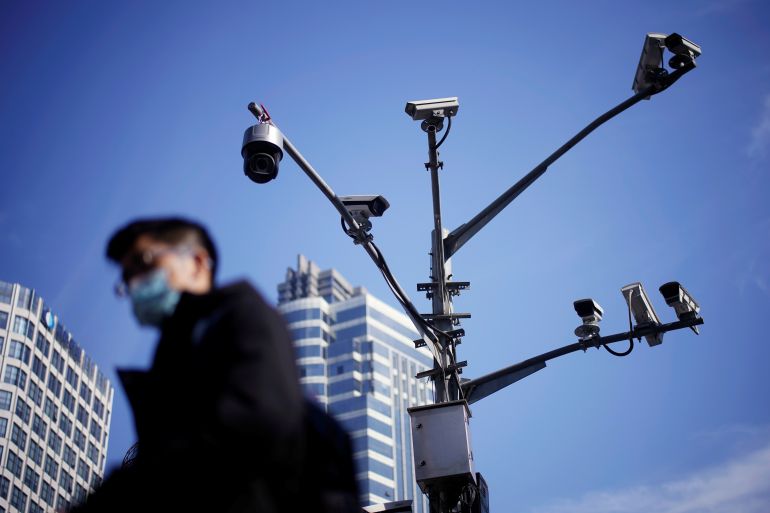 A man wearing a face mask walks past surveillance cameras following the coronavirus disease (COVID-19) outbreak, in Shanghai, China January 14, 2021. REUTERS/Aly Song