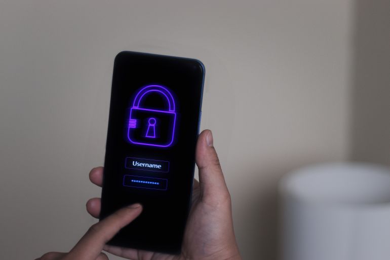 shutterstock_2236588087-1780919034-1 Cybersecurity in mobile phone against scam, hack and fraud. Encrypted smartphone. Password lock. Online data hacker. Cyber scammer using tech for phishing. Safety login app to protect personal privacy