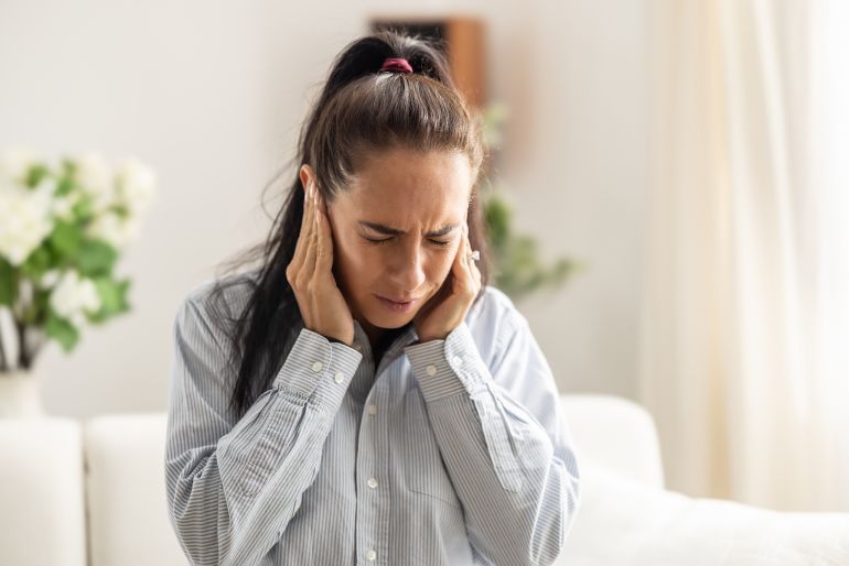 tinnitus3-1738856306 Young woman have headache migraine stress or tinnitus - noise whistling in her ears.