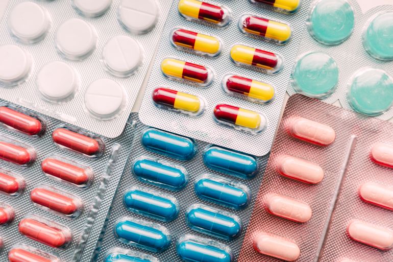 Top view of assorted prescription pills and capsules in colorful blister packs. Pharmaceutical medication background representing healthcare, drug treatment, medical industry, overmedication and pharmacy concept.