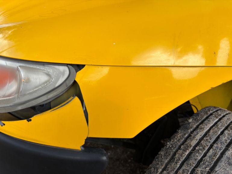 749906-1792762051 Close-up image of a yellow car's damaged front bumper and headlight for insurance or accident concept.
