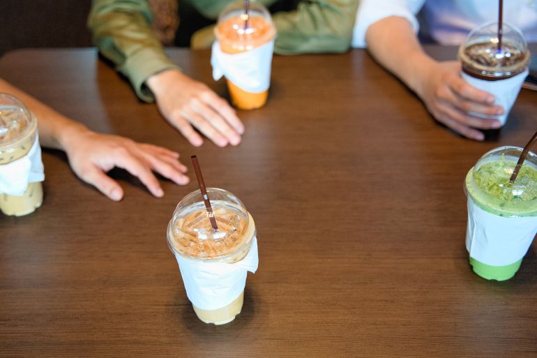 Hand of men meeting in the coffee shop with ice coffee and iced green tea.