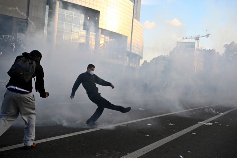 A protester kicks a tear gas canister during a demonstration of high-school students at Place de la Bastille, in Paris, on October 8, 2026, as part of a nationwide protest movement over learning conditions. Since late September, pupils have barred the entrances to hundreds of schools, complaining of teacher absences, overloaded timetables, dilapidated classrooms and buildings ill-adapted to rising temperatures, among other grievances. (Photo by JULIEN DE ROSA / AFP)