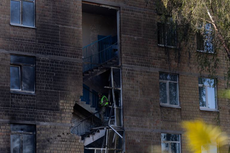 A police officer walks down the stairs searching for drone components that did not explode at a damaged school following a drone strike in Kyiv on October 1, 2026, amid the Russian invasion of Ukraine. (Photo by Tetiana DZHAFAROVA / AFP)