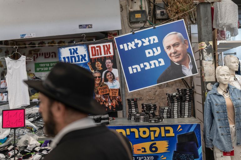 A man walks past a poster of Israel's Prime Minister Benjamin Netanyahu ahead of Israel's legislative election, at a market in Ramle on October 14, 2026.