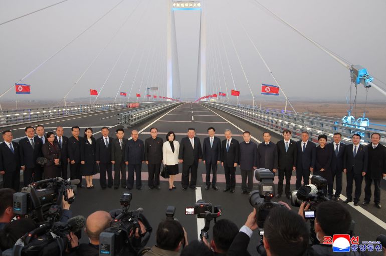 This picture taken on October 24, 2026 and released by North Korea's official Korean Central News Agency (KCNA) on October 25, 2026 shows North Korean leader Kim Jong Un (C) posing with Chinese and North Korean officials on the China-North Korea Yalu River Bridge in Dandong, China's Liaoning province.