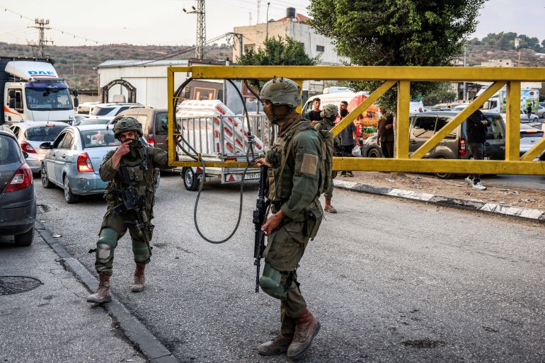 afp_6ae07506e813-1793094918 Israeli army soldiers close the vehicle barrier at the Deir Sharaf checkpoint, west of Nablus in the Israeli-occupied West Bank, on October 25, 2026.