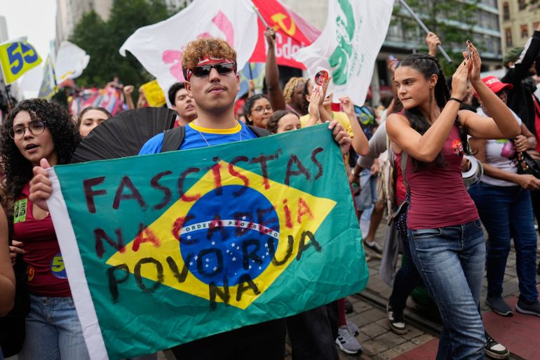 A demonstrator carries a sign that reads in Portuguese: "Fascists in jail, people in the streets" during a student march to defend public education and support Brazilian President Luiz Inacio Lula da Silva, who is running for a fourth term, ahead of the presidential runoff election in Rio de Janeiro, Wednesday, Oct. 7, 2026. (AP Photo/Silvia Izquierdo)