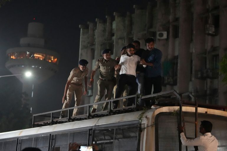 ap_6aca8530a86cd-1791657264 A man climb on a police vehicle is detained by police during a protest demanding the resignation of election chief Gyanesh Kumar, in Ahmedabad, India, Saturday, Oct. 10, 2026. (AP Photo/Ajit Solanki)