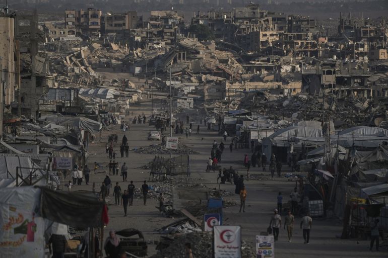 Palestinians walk along a street lined with buildings destroyed during the Israel-Hamas war in Gaza City Wednesday, Oct. 14, 2026. (AP Photo/Jehad Alshrafi)