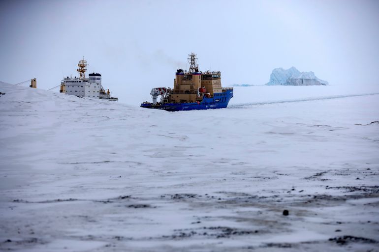 ap_6ad8a0813504e-1792581761 FILE - An Icebreaker makes the path for a cargo ship with an iceberg in the background near a port on the Alexandra Land island near Nagurskoye, Russia, May 17, 2021. (AP Photo/Alexander Zemlianichenko, File)