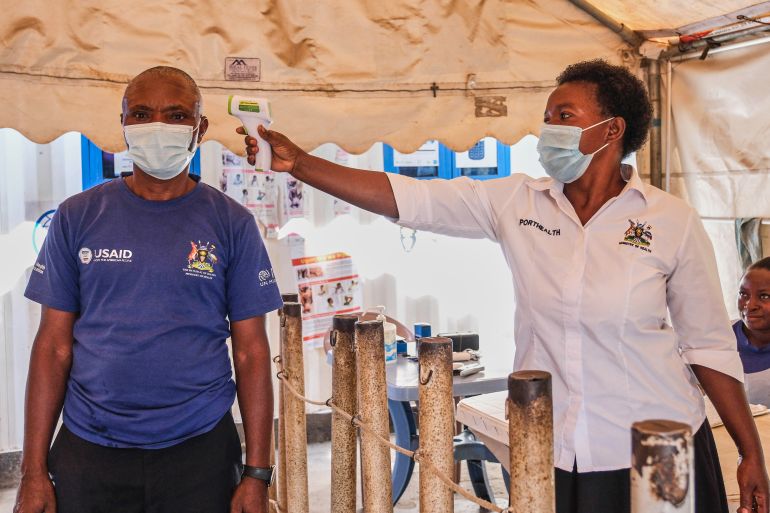 FILE - A health worker checks an individual's temperature at a temporary health clinic at the Mpondwe border crossing linking Uganda and the Democratic Republic of the Congo, June 4, 2026. (AP Photo/Hajarah Nalwadda, File)