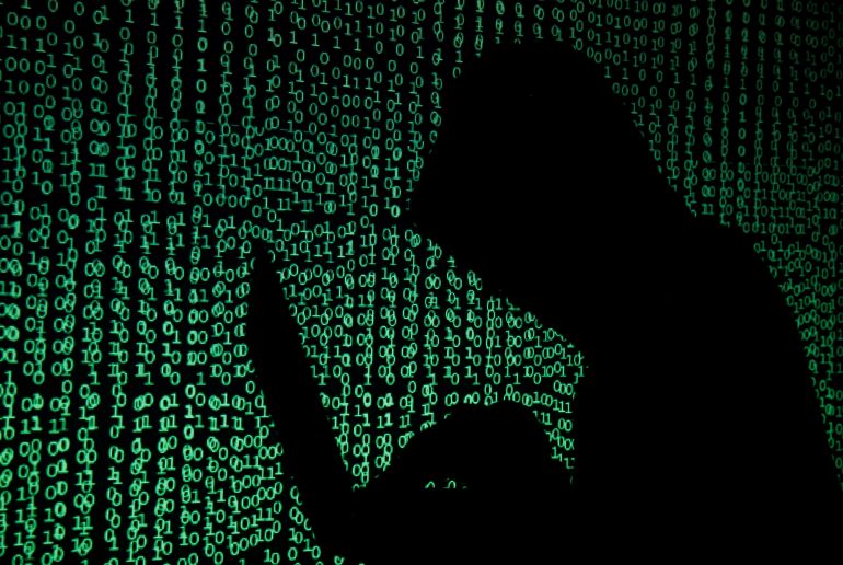 A hooded man holds a laptop computer as cyber code is projected on him in this illustration picture taken on May 13, 2017. Capitalizing on spying tools believed to have been developed by the U.S. National Security Agency, hackers staged a cyber assault with a self-spreading malware that has infected tens of thousands of computers in nearly 100 countries. REUTERS/Kacper Pempel/Illustration