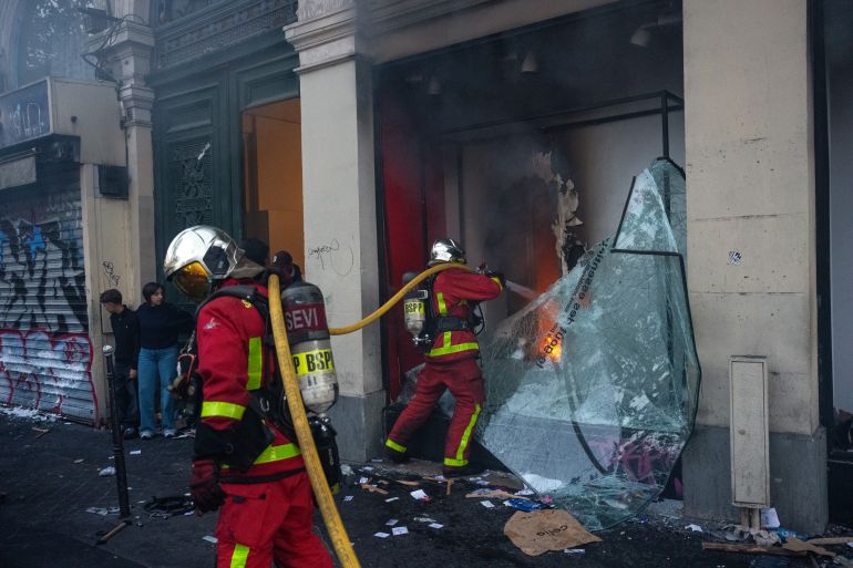 getty_6ad519bc1f-1792350652 PARIS, FRANCE - OCTOBER 17: Firefighters tackle a shop that was set on fire during demonstrations on October 17, 2026 in Paris, France. The involvement of the Gilets Jaunes (Yellow Vests) with the ongoing French school blockades expands the scope of these demonstrations by linking localised student grievances to broader economic policies. Student unions originally initiated the movement to protest underfunding, deteriorating infrastructure, and acute teacher shortages across French high schools and universities. By joining the protests, the Gilets Jaunes introduce their established platform against austerity cuts, rising living costs, and surging fuel prices into the youth-led action. (Photo by Carl Court/Getty Images)