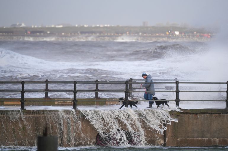 getty_6ade4ffb98-1792954363 NEW BRIGHTON, UNITED KINGDOM - OCTOBER 25: A person walks their dogs along the sea wall as waves created by the high winds of Storm Boelo hit the sea wall at New Brighton promenade on October 25, 2026 in New Brighton, United Kingdom. An amber warning remains in place on Sunday for strong winds across northern parts of the UK, with the storm causing travel disruptions and power cuts. Storm Boelo became the second named storm affecting the UK in 48 hours, following hot on the heels of Storm Austen, which battered southern England and Wales with strong winds and rain. (Photo by Christopher Furlong/Getty Images)