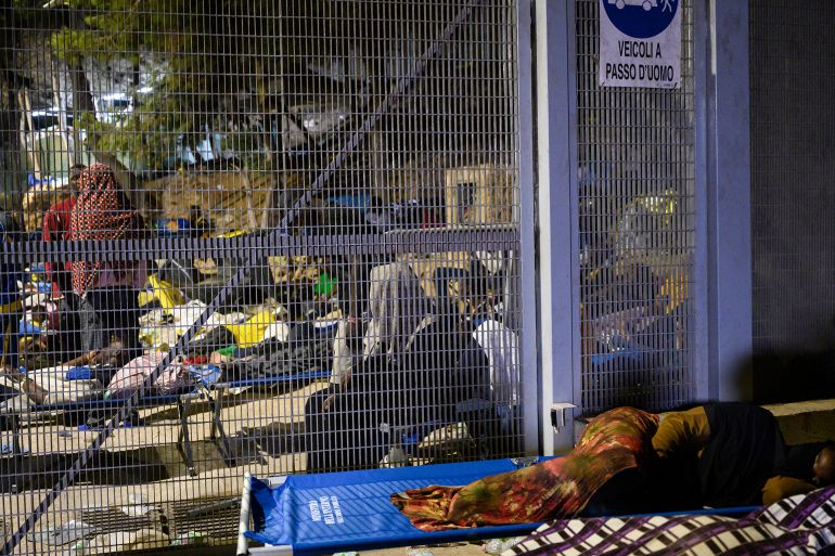 A man sleeps outside the Lampedusa's migrant reception center, Sicily, Italy, early Thursday Sept. 14, 2023. The reception center in Italy's southernmost island of Lampedusa remained critical Thursday as it coped with transferring to the mainland thousands of migrants who arrived on small, unseaworthy boats in a 24-hour span this week. (AP Photo/Valeria Ferraro)