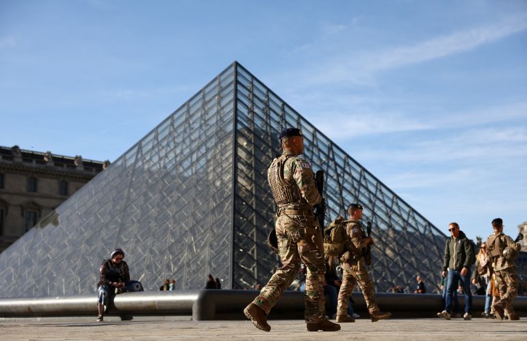 louvre12-1761851099 French soldiers from the "Sentinelle" security plan patrol past the glass Pyramid of the Louvre Museum as French police have arrested more suspects linked to the theft of treasures from the Louvre museum's Galerie d'Apollon (Apollo gallery), in Paris, France, October 30, 2025. REUTERS/Abdul Saboor