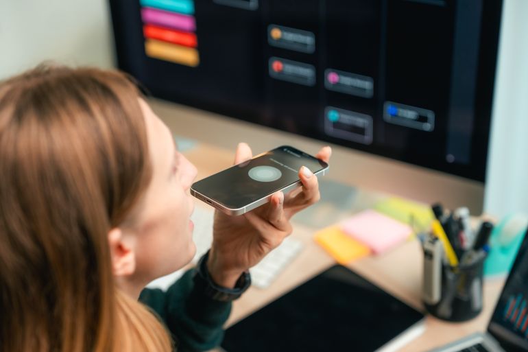 new-1784023276 Modern woman using voice commands on her smartphone to interact with AI assistant app, efficiently managing her work schedule hands-free to stay productive and organized during a busy remote workday adobe stock
