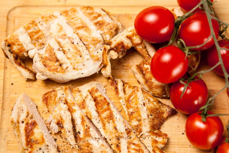 Organic delicious food. Fresh grilled chicken breast on wooden board next to tomatoes. Healthy dinner and lifestyle (ماغنيفيك)
