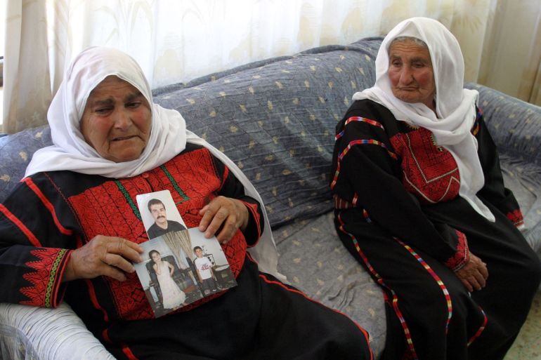 res-1701687162 The mother (L) of Ibrahim Hamed, the West Bank supremo of the armed wing of governing Islamist movement Hamas, wearing a traditionally embroidered Palestinian dress shows off the photograph of her son and his children at her home in the village of Silwat close to the West Bank town of Ramallah 23 May 2006. Hamed, the 41-year-old leader of the Ezzedin al-Qassam Brigades in the West Bank, was arrested early this morning by the Israeli military from his home in Ramallah. He has been on Israel's wanted list since 1998 but had previously escaped capture or assassination, in part by keeping perpetually on the move. AFP PHOTO/ABBAS MOMAN (Photo by ABBAS MOMANI / AFP)