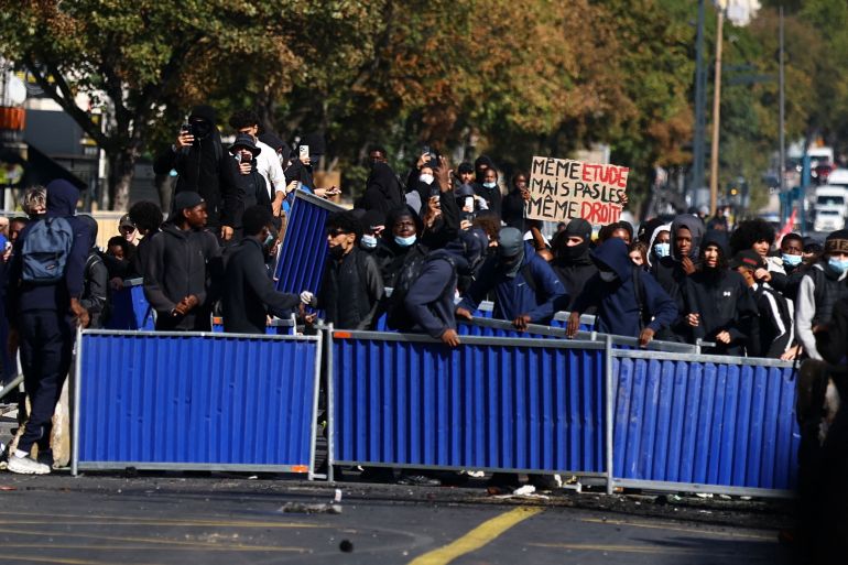 reuters_6abffcca-1790966986 Masked protesters install a barricade amid clashes with police during a protest by high school students near the Lycee Berthelot high school in Aubervilliers near Paris as part of nationwide protests to demand the hiring of substitute teachers, increased resources and better learning conditions, as more than 400 schools remain closed following days of student protests that have escalated into violence in some places, France, October 2, 2026. The slogan on the placard reads "Same studies, but not the same rights". REUTERS/Sarah Meyssonnier