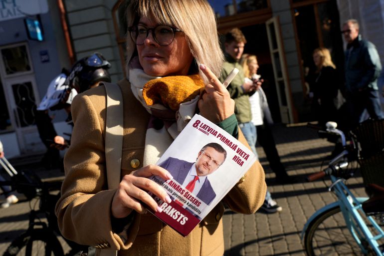 reuters_6ac02a95-1790978709 FILE PHOTO: A woman holds an election campaign leaflet of the "Latvia First" party with a picture of the party's leader, Ainars Slesers, before the general election in Riga, Latvia, September 27, 2026. REUTERS/Ints Kalnins/File Photo