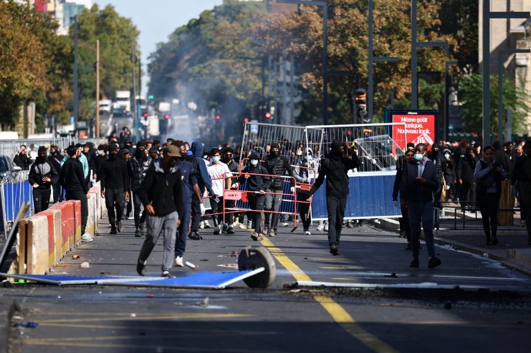 reuters_6ac2b02f-1791143983 Masked protesters react in a street amid clashes during a protest by high school students near the Lycee Berthelot high school in Aubervilliers near Paris as part of nationwide protests to demand the hiring of substitute teachers, increased resources and better learning conditions, as more than 400 schools remain closed following days of student protests that have escalated into violence in some places, France, October 2, 2026. REUTERS/Sarah Meyssonnier