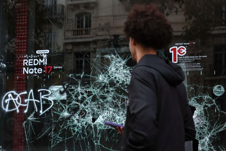 reuters_6ad4c625-1792329253 A person walks past the broken window of a Free shop, the day after clashes during a national day of demonstrations against the cost of living and rising fuel prices, in Marseille, France, October 18, 2026. REUTERS/Manon Cruz