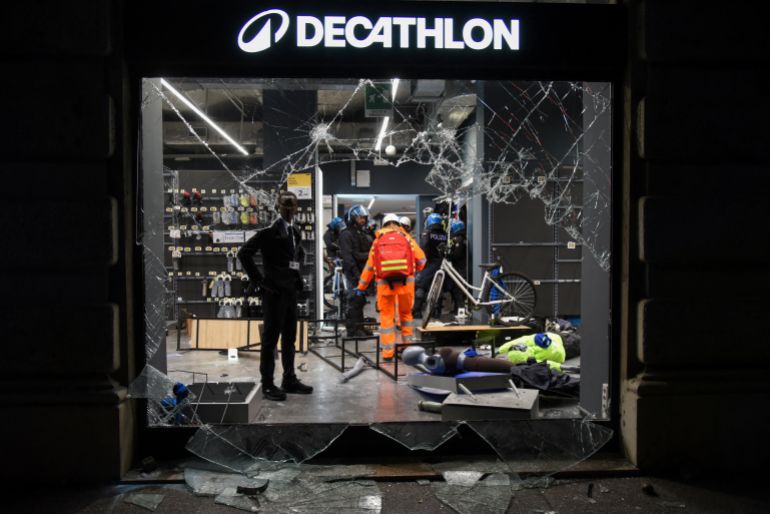 reuters_6ad51d46-1792351558 Police officers stand inside a Decathlon sporting goods store behind shattered glass during a protest over the state of public services and the rising cost of living in Milan, Italy, October 18, 2026. REUTERS/Stringer
