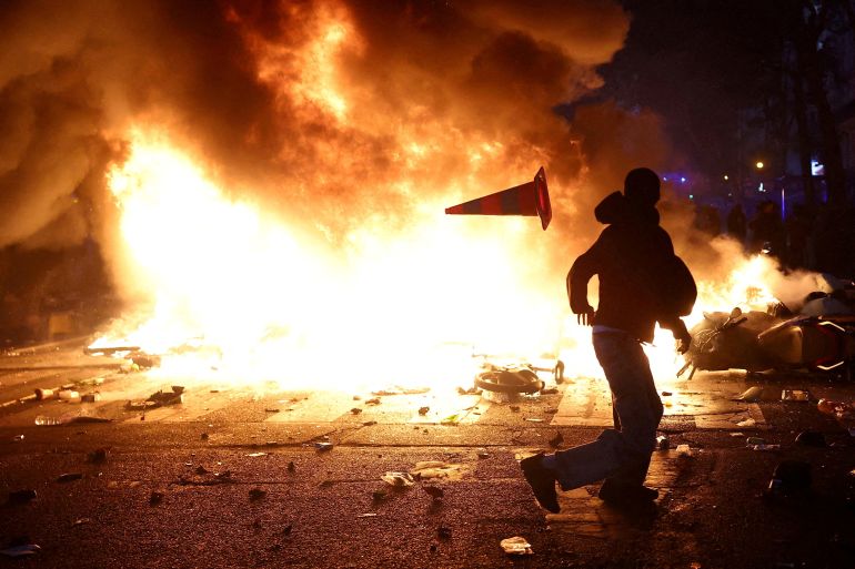 FILE PHOTO: A man throws a plastic traffic cone through a burning barricade amid clashes during a day of demonstrations against the cost of living and rising fuel prices in Paris as part of nationwide protests called by the "Yellow Vests" movement, joined by French high school and university students, teachers and parents demanding better school conditions and government action, as well as labour unions, workers, farmers and retirees, France, October 17, 2026. REUTERS/Abdul Saboor/File Photo/File Photo