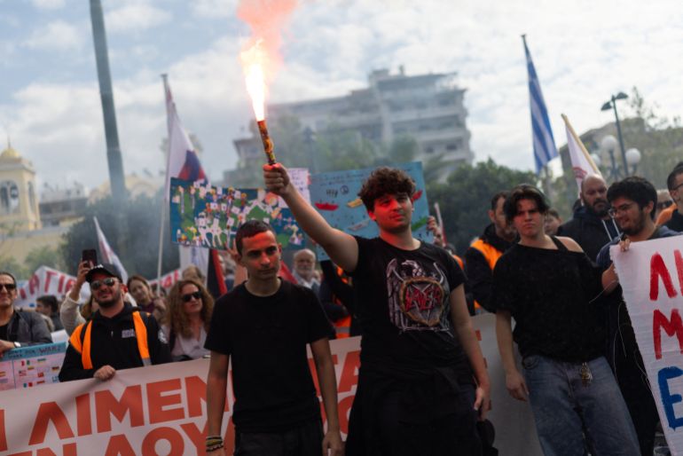 reuters_6ae4c4db-1793377499 A student holds a flare at an anti-war rally during a 24-hour strike by seafarers, in Piraeus, Greece, October 30, 2026. REUTERS/Stelios Misinas