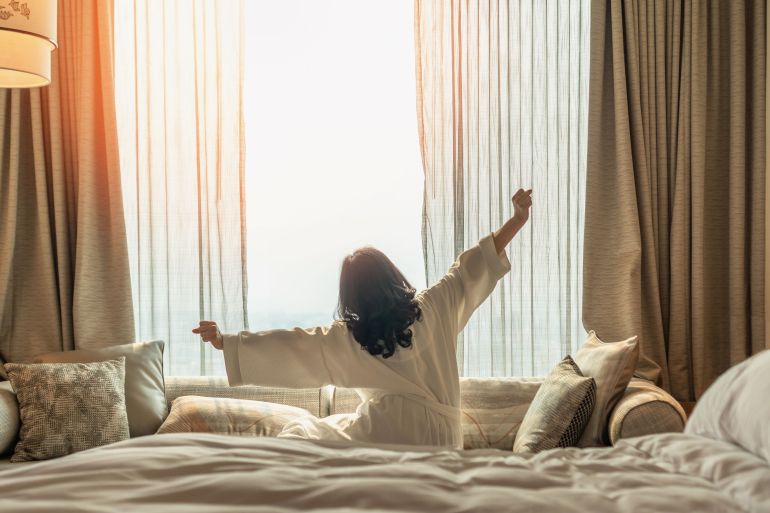 sleep1-1730130898 Hotel relaxation on lazy day with Asian woman waking up from good sleep on bed in weekend morning resting in comfort bedroom looking toward city view, having happy, work-life quality balance lifestyle; Shutterstock ID 2455925403; purchase_order: aljazeera ; job: ; client: ; other: